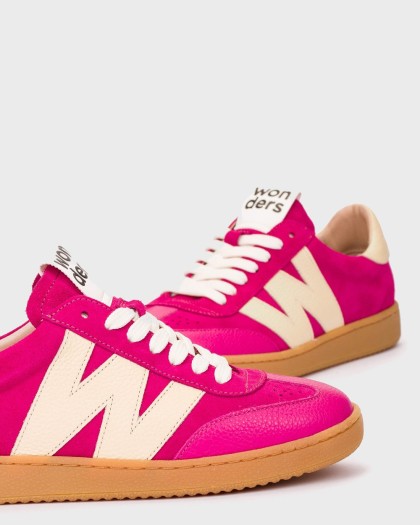 Primer plano del par de deportivas NUBIA 01 en fucsia y blanco roto con cordones blancos y suela color caramelo.